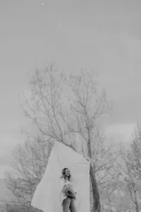A woman stands in front of a sheet