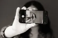 A woman takes a selfie with the phone pointed towards the viewer