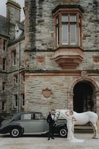 Bride and groom posing with horse and car in front of Ireland castle