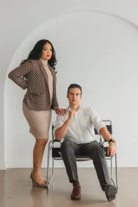 Two people pose with a chair