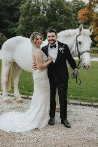 Bride and groom posing in front of white horse
