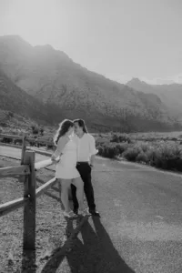 Engaged couple leaning up against fence with Nevada mountains in the back