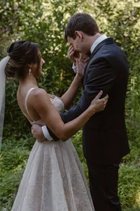 Bride embraces the emotional groom during their first look in a lush green forest before their Alaska elopement.