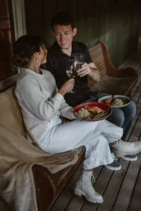 Newlyweds toast with wine while enjoying an intimate dinner together on the cabin porch after their Alaska elopement.