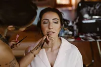 Close-up of the bride with her eyes closed as a makeup artist applies lip color before the Alaska elopement.