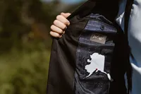 Groom holds open his suit jacket to reveal a custom lining embroidered with the outline of Alaska and a red heart.