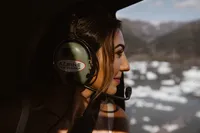 Close-up of the bride wearing a helicopter headset as she looks out at the icy Alaska landscape during the flight.