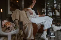 Newlyweds relax together on the cabin porch after their Alaska elopement, smiling with a glass of wine in hand.