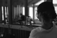Black-and-white photo of the bride video calling a smiling woman while getting ready for her Alaska elopement.