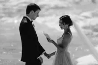 Black-and-white photo of the bride reading her private vows while holding the groom’s hand on an Alaska glacier.