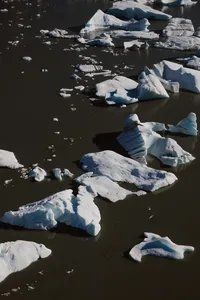 Aerial view of jagged blue-white icebergs floating in dark glacial water in the Alaska wilderness.