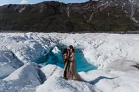 Newlyweds kissing in front of an ice glacier during their Alaskan Elopement.