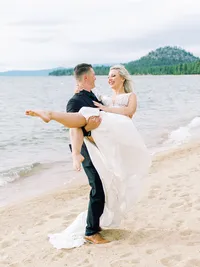 groom carries his bride on lake tahoe beach