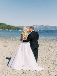 bride and groom kissing facing lake tahoe