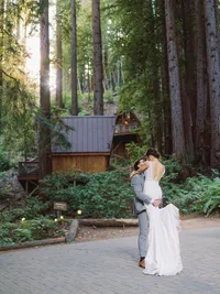 groom picks up bride in woodsy area