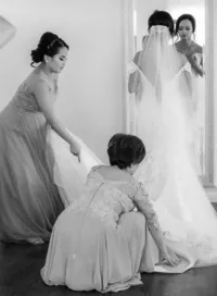 brides mother and bridesmaid helping bride to get ready