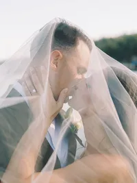 bride and groom kissing with veil covering them on Gar Woods beach during the sunset