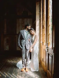 bride and groom first look in waterfall lodge barn near patio windows with sunlight peeking through