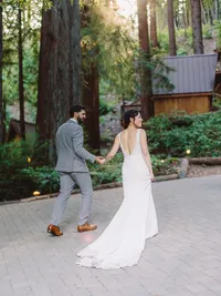 bride and groom holding hands and walking in the woodsy area