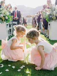 flower girls picking up white rose petals after wedding ceremony in Everline resort