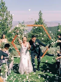bride and groom walking down the isle as guests throwing white rose petals at them at Tannenbaum wedding venue in tahoe