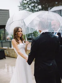 bride and groom holding umbrellas at their wedding ceremony during rain
