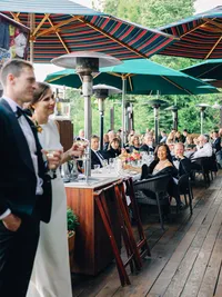 Bride and groom listening to parents give the speech and guests watching