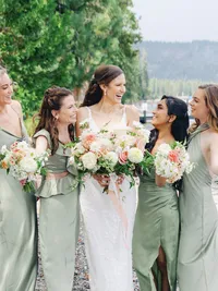 bride and her bridesmaids laughing on the beach and holding beautiful bouquets