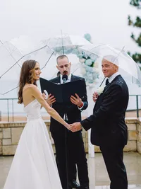 bride and groom holding hands at their rainy wedding ceremony