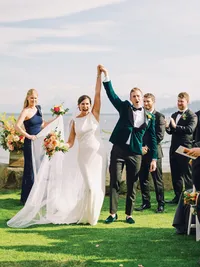 bride and groom holding hands and cheering right after the ceremony kiss