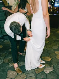 groom fixing brides dress at their wedding reception