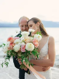 sunset photo of bride and groom covering themselves with huge bouquet
