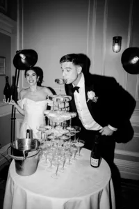groom sipping champagne from a champagne tower with bride holding the bottle at their andaz hotel wedding