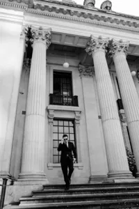 fashion forward editorial portrait of a groom in black and sunglasses walking down steps of marylebone town hall