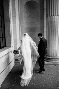 nostalgic wedding photo of bride with a long veil and groom at old marylebone town hall steps
