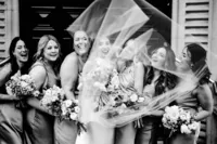 Candid fun wedding photography of bride and bridesmaids covered by veil outside Andaz london