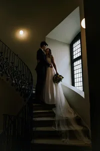 moody and cinematic wedding portrait of bride and groom kissing at the queens house tulip staircase