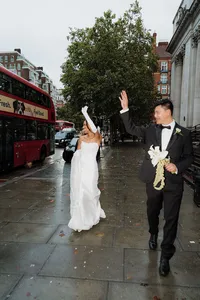 candid documentary wedding photo of bride and groom waving at guests on a rainy day at marylebone