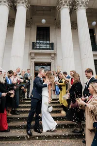 candid wedding photography of bride and groom sharing a kiss during confetti on steps of marylebone town hall in london