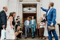 same sex wedding with two grooms in blue suits exiting marylebone town hall through confetti tunnel