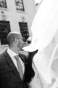 creative modern photo of bride and groom kissing with veil flowing in wind