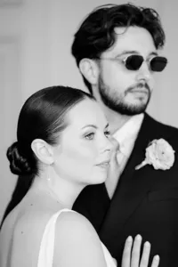 editorial fashion forward wedding portrait with bride in front and groom wearing sunglasses in the background