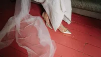 close up creative photo of bride's shoes on a red floor with veil around by film wedding photographer