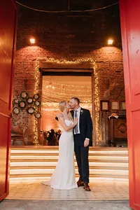 Couple sharing a kiss with red venue interiors behind by warsaw wedding photographer