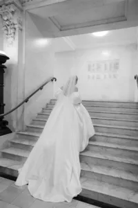 editorial wedding photo of bride in a long white dress and veil walking up stairs of marylebone town hall wedding venue