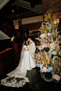bride and groom kissing next to flowers at the connaught hotel in london