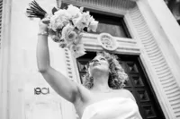Modern vintage wedding portrait of bride lifting flowers up captured o black and white film outside 1901 ballroom