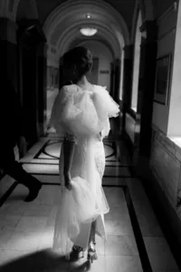cinematic black and white photo of bride walking into Islington town hall ceremony in dress with a big bow at the back