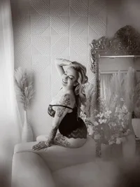 Black and white portrait of a woman posing beside an ornate mirror, luxury boudoir photography
