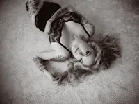 Black and white overhead portrait of a woman in lace lingerie lying on a rug, fine art boudoir photography